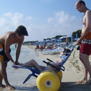 Zwei Mnner mit Mann im Rollstuhl am Strand